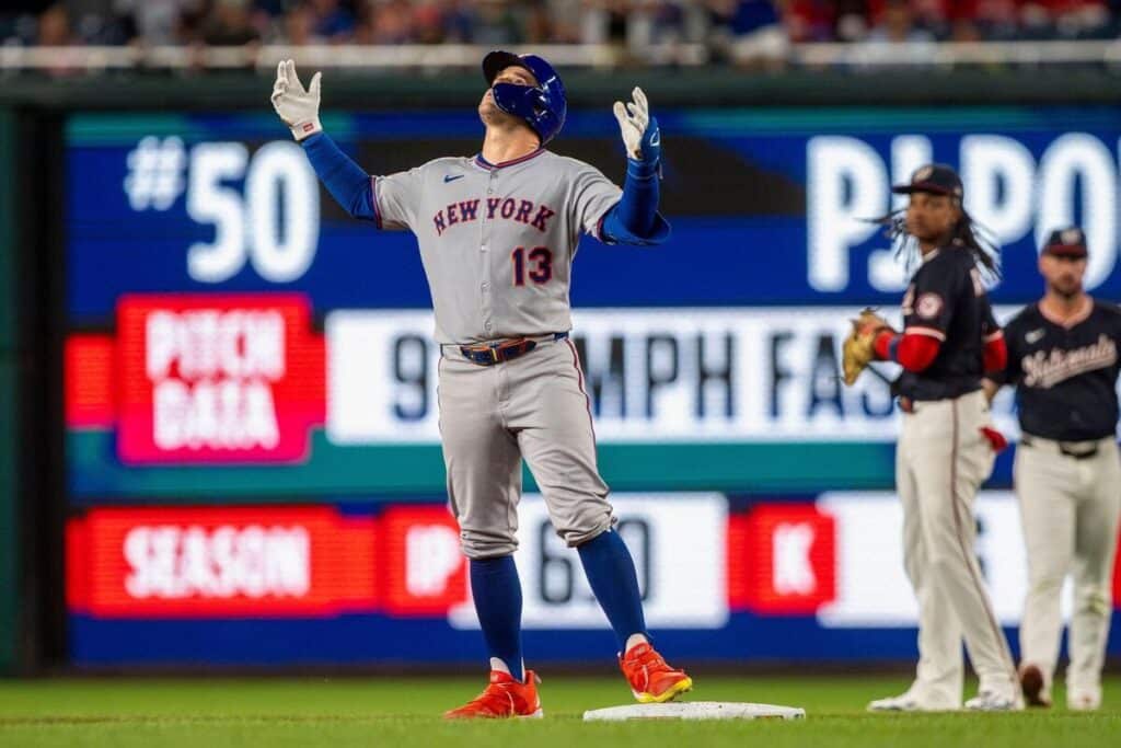New York Mets center fielder Luis Torrens holds his arms up in the air while looking at the sky.