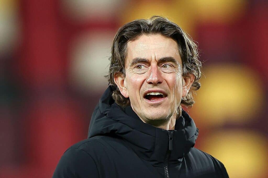 Tottenham Hotspur Football Club manager Thomas Frank looking to his side and opening his mouth while wearing a black coat